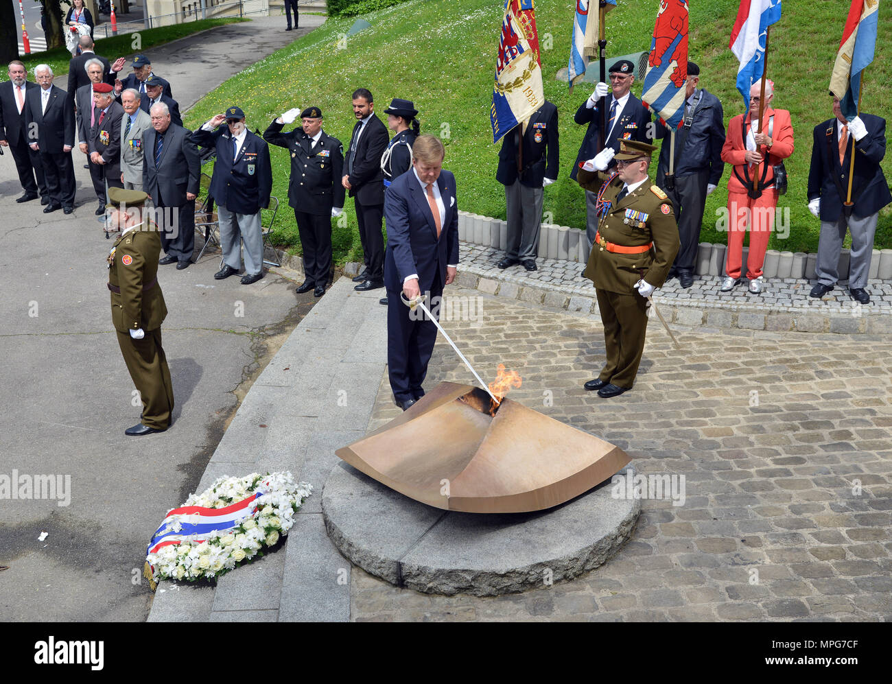 23 May 2018, Luxembourg, Luxembourg: Dutch King Willem-Alexander (c) holds a sword into the flames of the Monument de Solidarité. The Dutch King and Queen are in Luxembourg for a three-day state visit. Photo: Harald Tittel/dpa Stock Photo