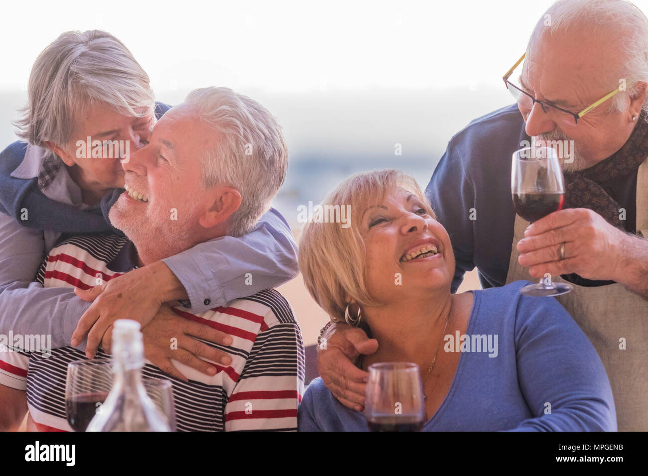 causasian mature couples friends having fun during evening dinner together. kiss and hug and smile and laugh for great retired lifestyle concept. outd Stock Photo