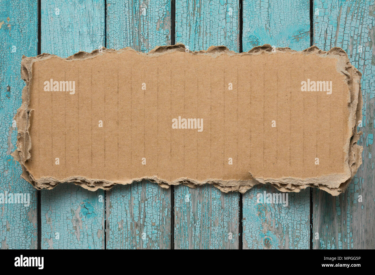 Rip cardboard piece on blue vintage wood background Stock Photo