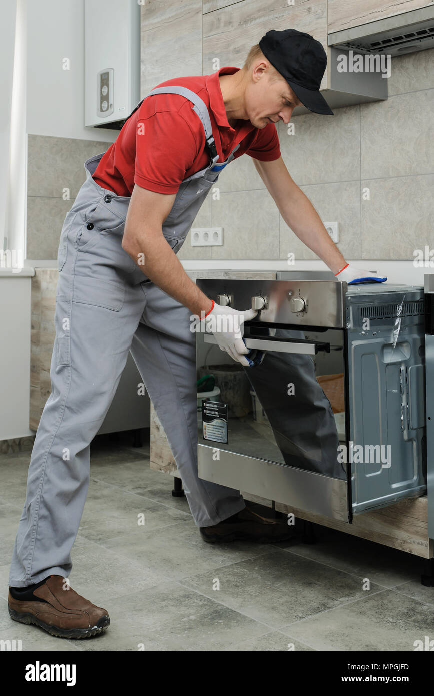 Installation of household appliances. Workman installing a builtin electric oven Stock Photo