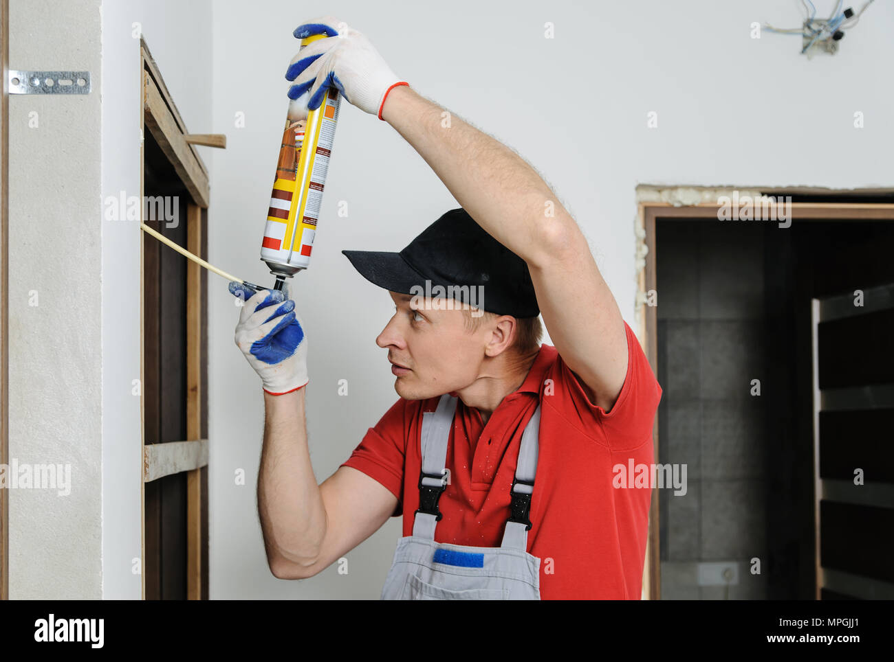 Installing door unit. Workman fixed the door frame using mounting foam. Stock Photo