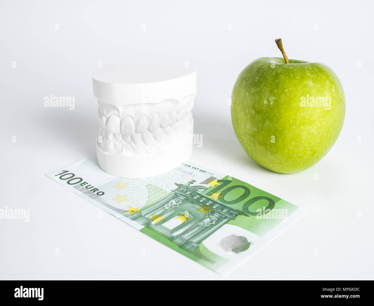 The green apple, the denture and the one hundred euro bill isolated close up Stock Photo