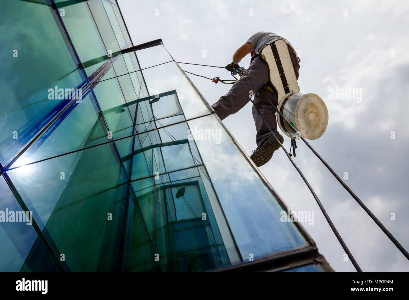 Industrial climber, alpinist, is adjusting climbing gear, preparing safety ropes. Stock Photo