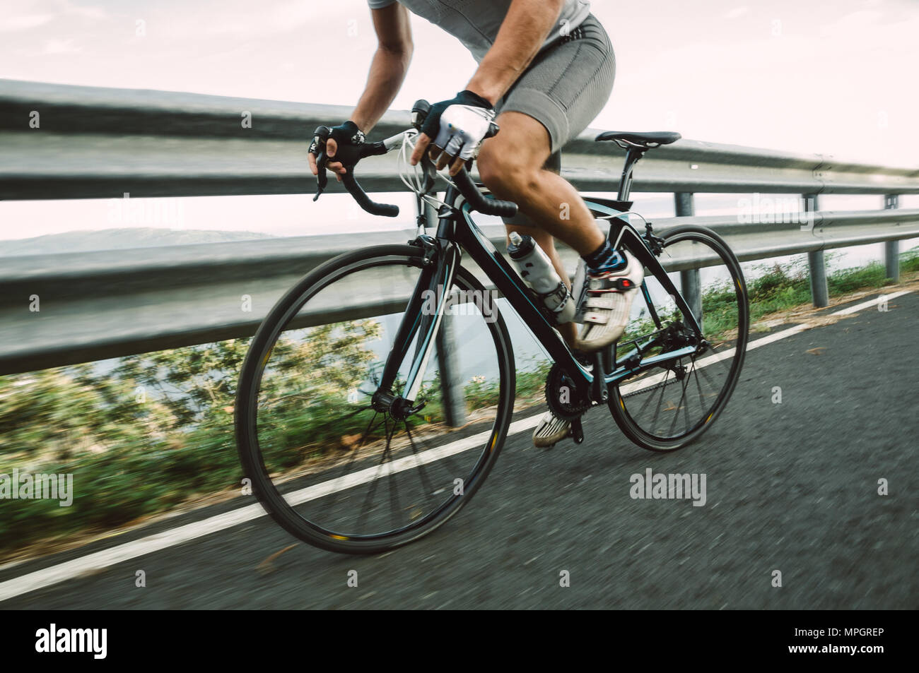 Detail of a road bike with a cyclist pedaling on a road. Stock Photo