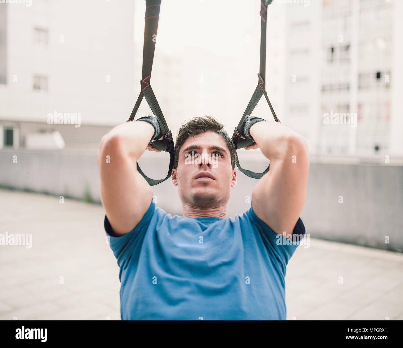 Sporty male exercising with fitness trx straps in the street Stock Photo