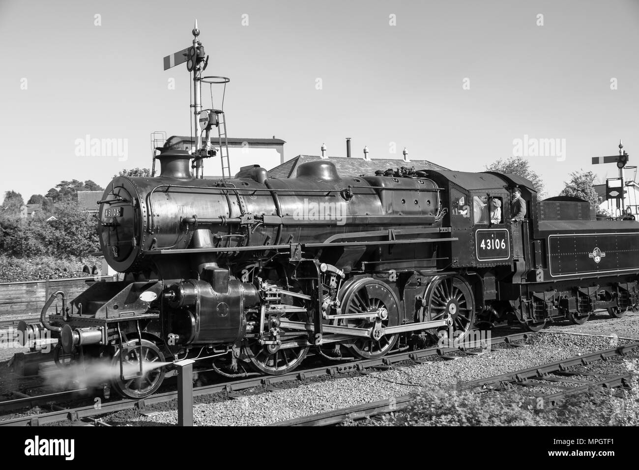 Black & white side view close up of vintage UK steam locomotive in action approaching station on Severn Valley heritage railway line in sunshine. Stock Photo