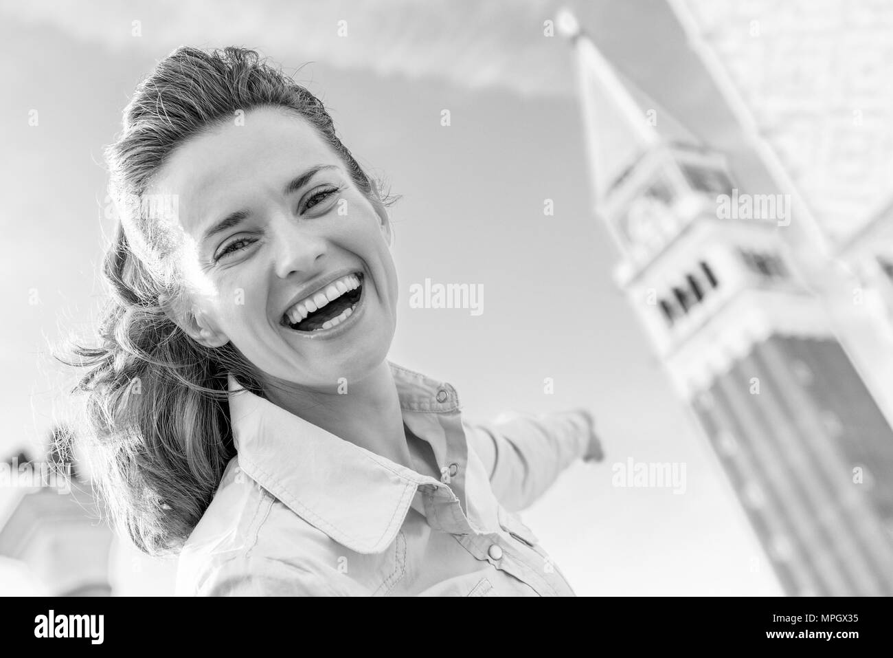 Happy young woman pointing on campanile di san marco in venice, italy Stock Photo