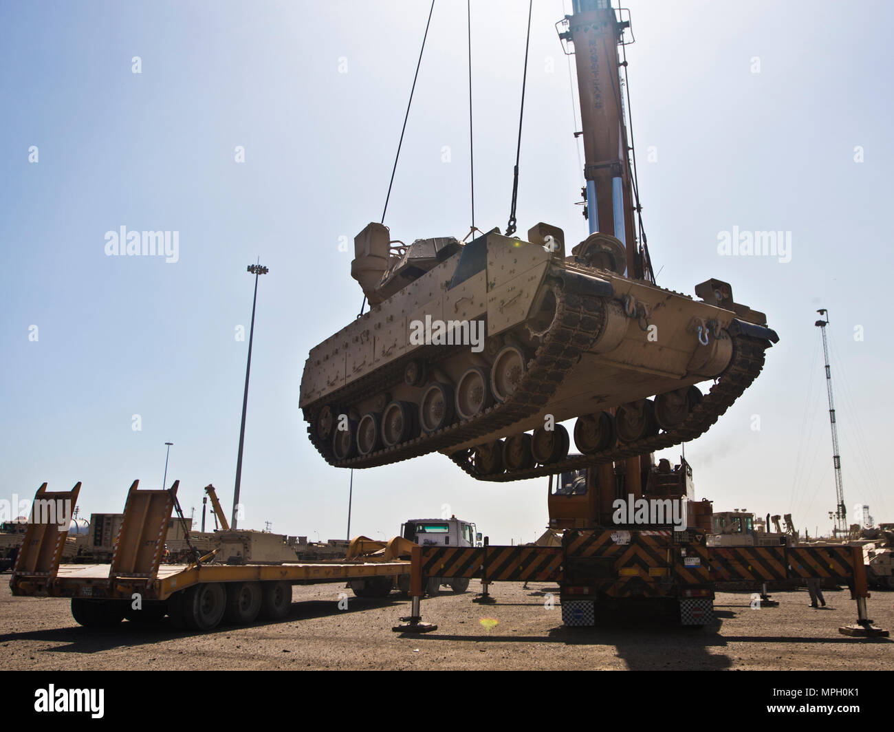 A M2/M3 Bradley Fighting Vehicle is transported via crane onto a flat bed truck to be put on the USNS Mendonca at Shuaiba Port, Kuwait, on Feb. 28, 2017. The Mendonca is used to import and export U.S. Military vehicles in support of operations in the USCENTCOM AOR. (U.S. Army Photo by Staff Sgt. Dalton Smith) Stock Photo