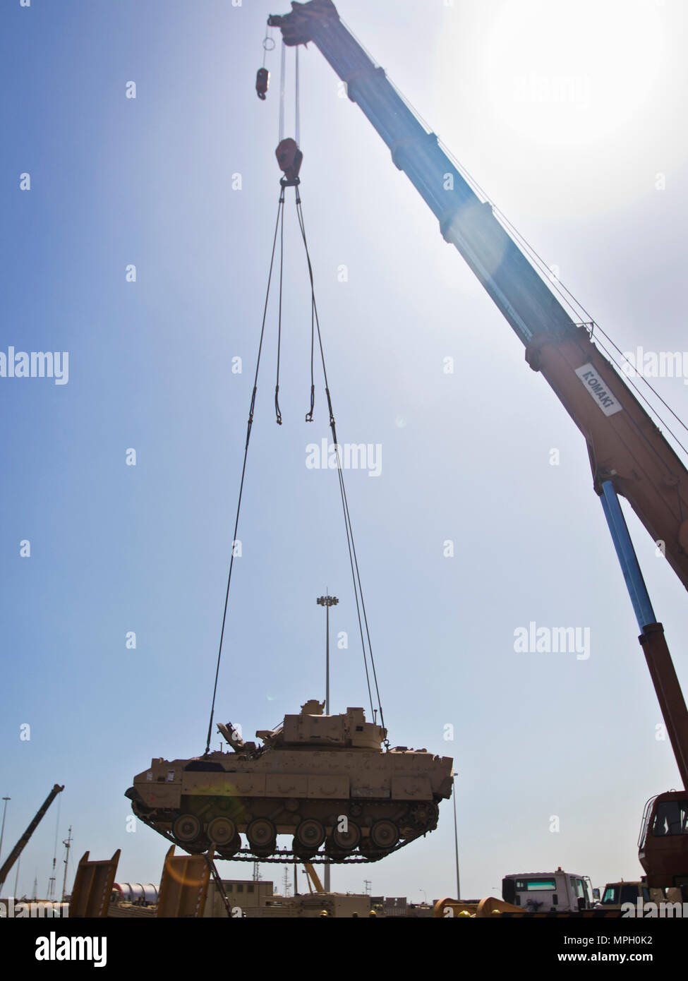 A M2/M3 Bradley Fighting Vehicle is transported via crane onto a flat bed truck to be put on the USNS Mendonca at Shuaiba Port, Kuwait, on Feb. 28, 2017. The Mendonca is used to import and export U.S. Military vehicles in support of operations in the USCENTCOM AOR. (U.S. Army Photo by Staff Sgt. Dalton Smith) Stock Photo