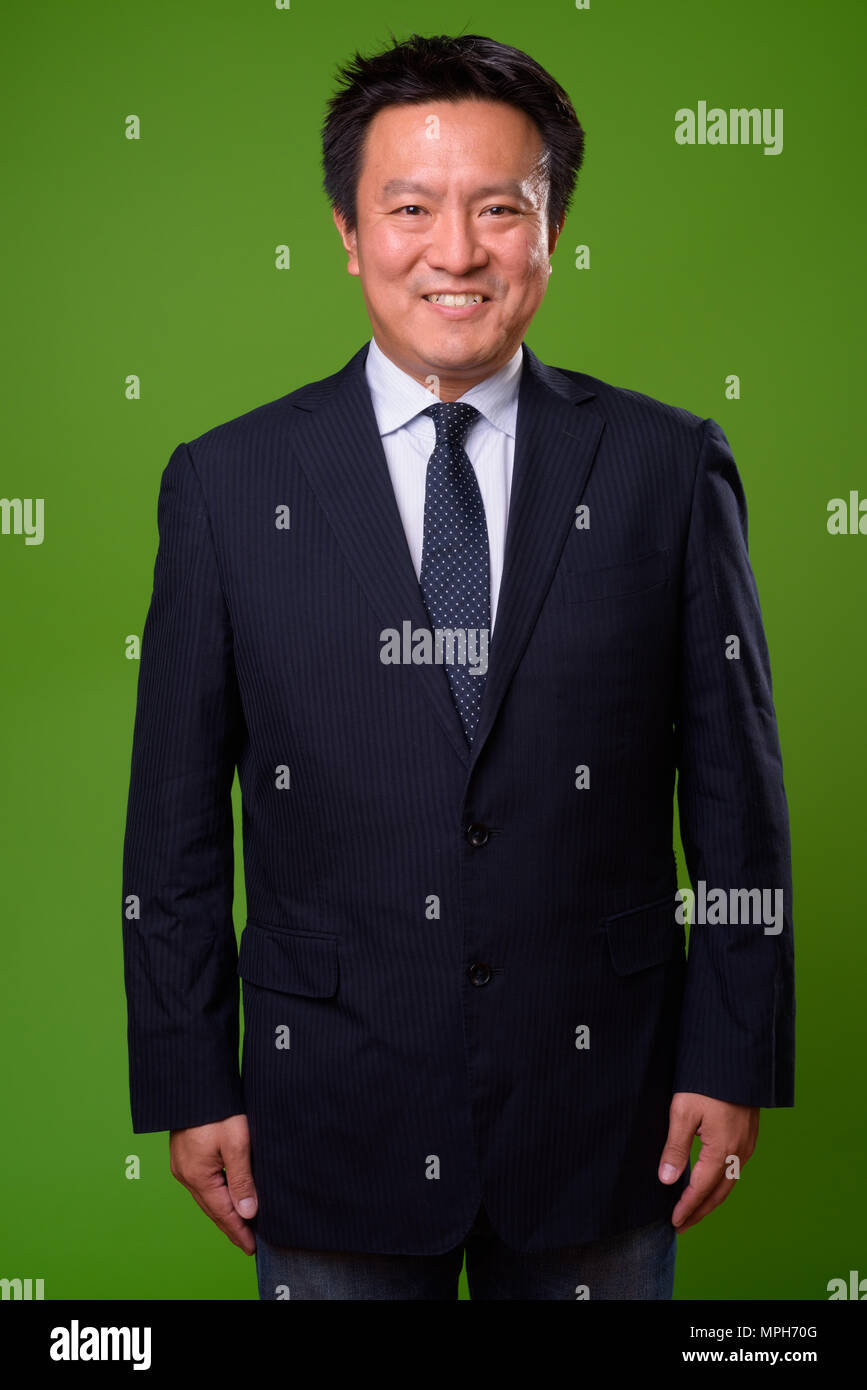 Mature Japanese businessman against green background Stock Photo