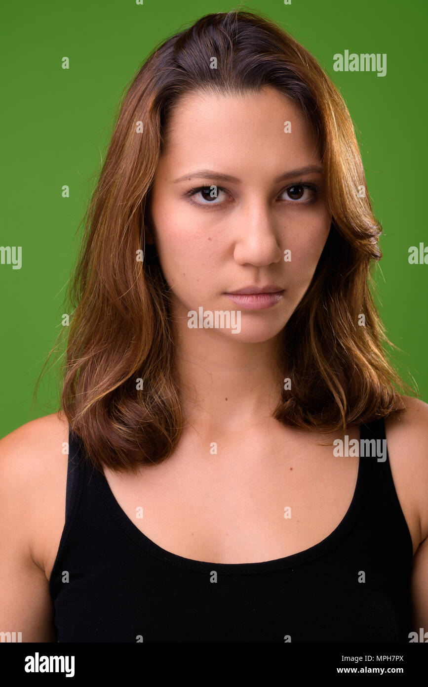 Young beautiful multi-ethnic woman against green background Stock Photo