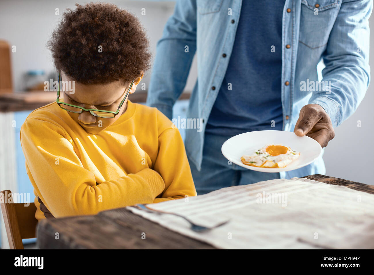 Stubborn pre-teen boy not wanting fried egg for breakfast Stock Photo