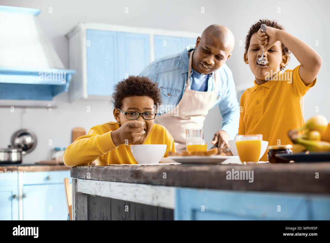 Caring young father watching his children eat breakfast Stock Photo Alamy