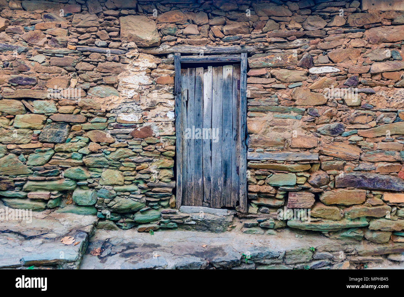 View of old Rustic wooden door and big rocks wall for  space  for editing Stock Photo - Alamy
