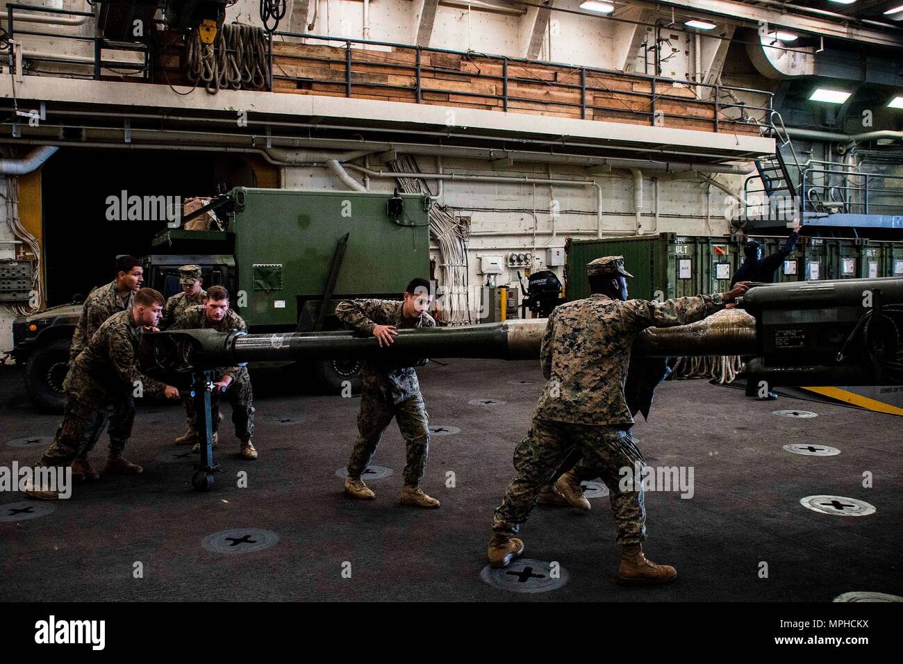 170314-N-JH293-235 OKINAWA, Japan (March 14, 2017) Marines assigned to the 31st Marine Expeditionary Unit (MEU) push an M777 Howitzer through the vehicle storage area of the amphibious transport dock ship USS Green Bay (LPD 20). Green Bay, part of the Bonhomme Richard Expeditionary Strike Group, with embarked 31st MEU, is on a routine patrol, operating in the Indo-Asia-Pacific region to enhance warfighting readiness and posture forward as a ready-response force for any type of contingency. (U.S. Navy photo by Mass Communication Specialist 1st Class Chris Williamson/Released) Stock Photo