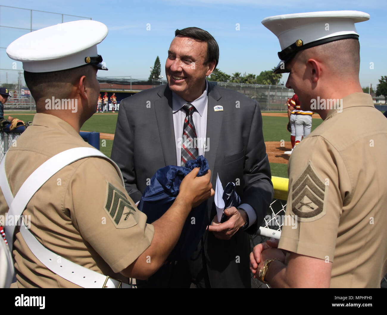 Marine Corps Recruiters SSgt. Phillip Page and Sgt. Victor Romauldo of Recruiting Substation Lakewood present a gift of appreciation for the Honorable Dan Koops, Mayor of Bellflower City, before a baseball varsity game at St. John Bosco High School in Bellflower, Calif., March 14, 2017. Stock Photo