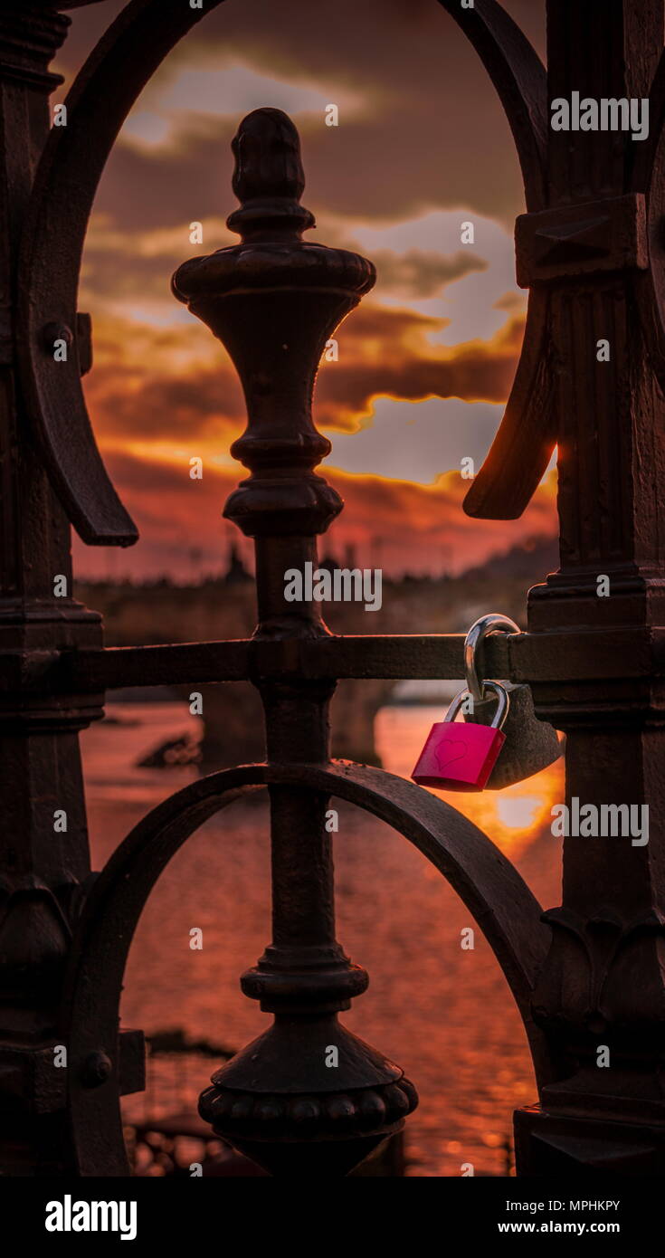 Red lock with a heart engraved on it locked to the rail of a bridge ...