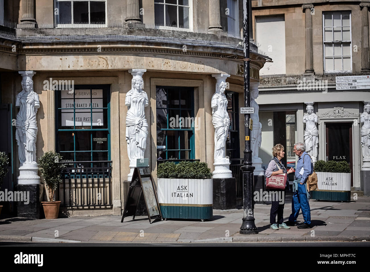 Man and woman talking in the street outside of an Italian restaurant in the Montpellier district of Cheltenham, Gloucestershire.= Stock Photo