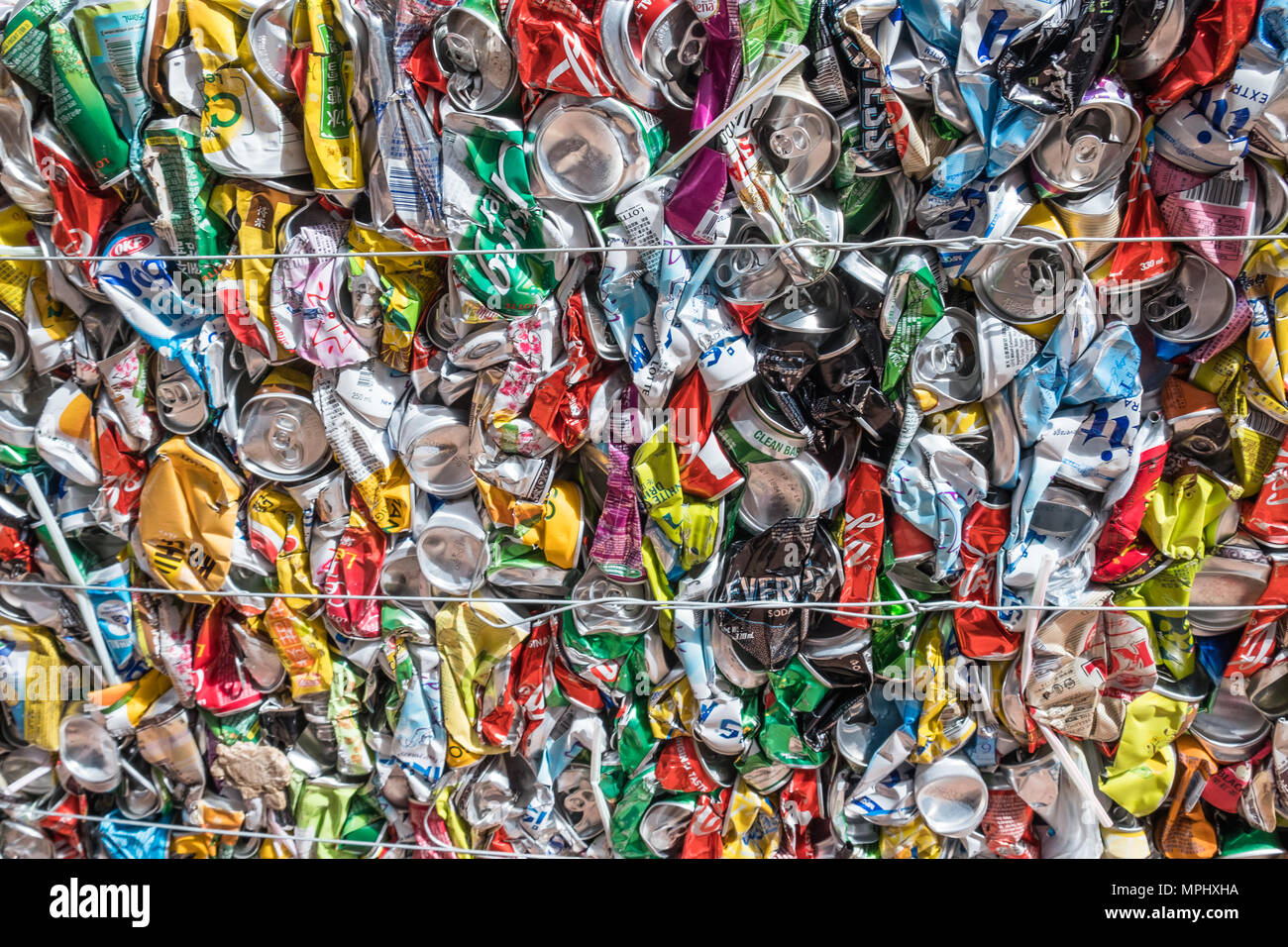 Squeezed aluminum beer and beverage cans prepared for transportation and processing pressed together into a cubic shape. Urban scene. Stock Photo