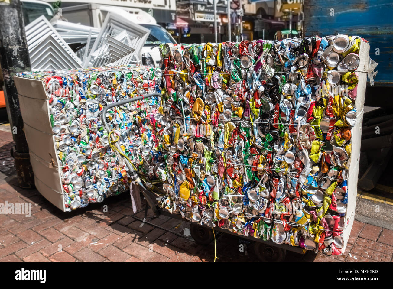 Squeezed aluminum beer and beverage cans prepared for transportation and processing pressed together into a cubic shape. Urban scene. Stock Photo