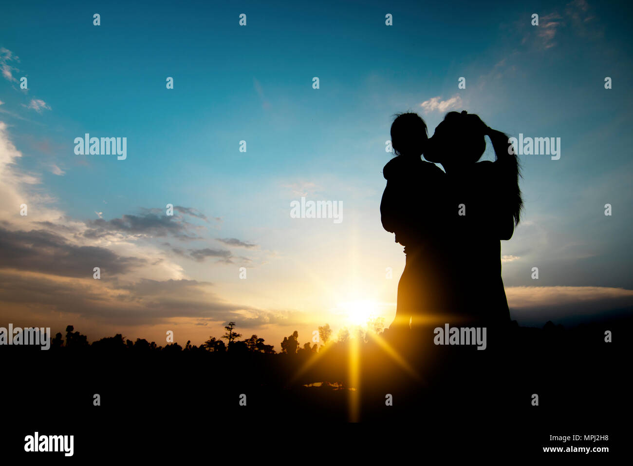 Family and Single mom concept, silhouette of women carrying daughter and kiss her in sunset Stock Photo