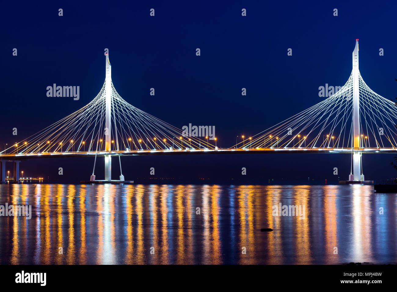 Cable-stayed bridge connects the roads of Western high-speed diameter in St. Petersburg, Russia. Night lighting of bridge is reflected in water of Pet Stock Photo