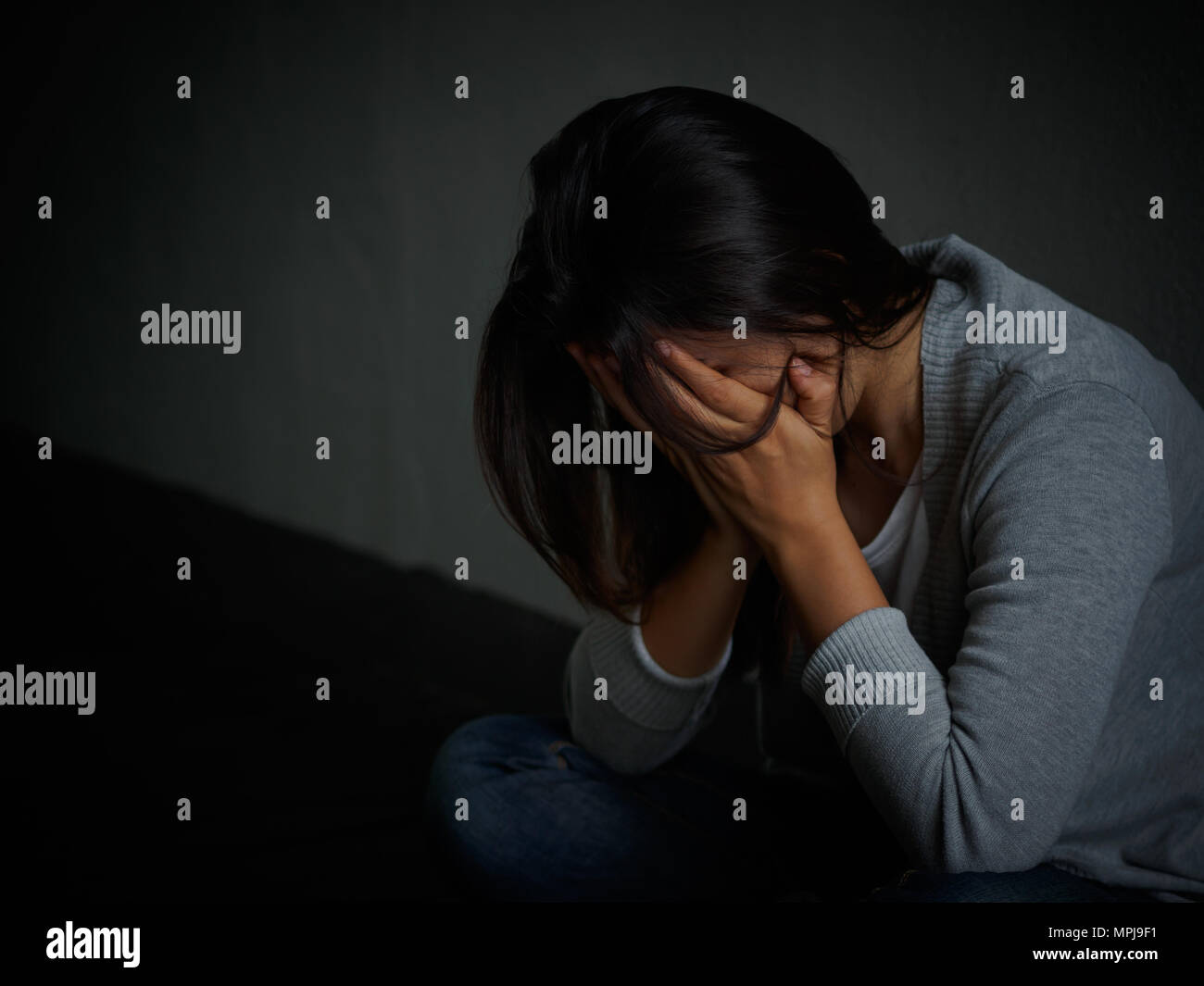 sad woman hug her knee and cry Sad woman sitting alone in a empty room 