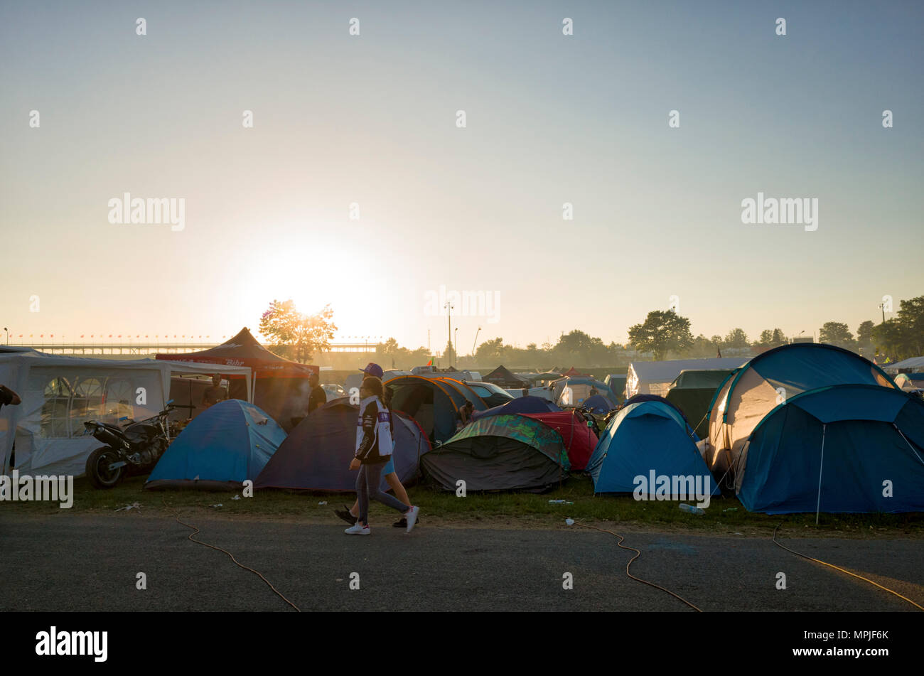 19-20th May 2018. Le Mans, France. Behind the scenes at the MotoGP. The sun  sets over the race circuit and campsite in the late evening. A couple walk  past the campsite tents