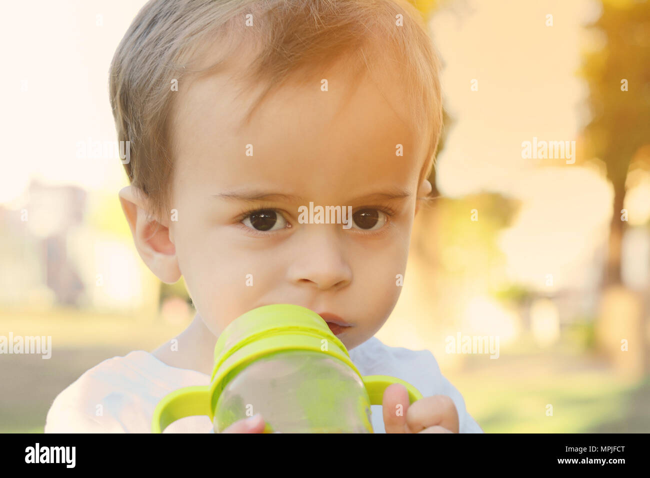 Cute Baby Boy Drinking Milk Bottle in a park Stock Photo