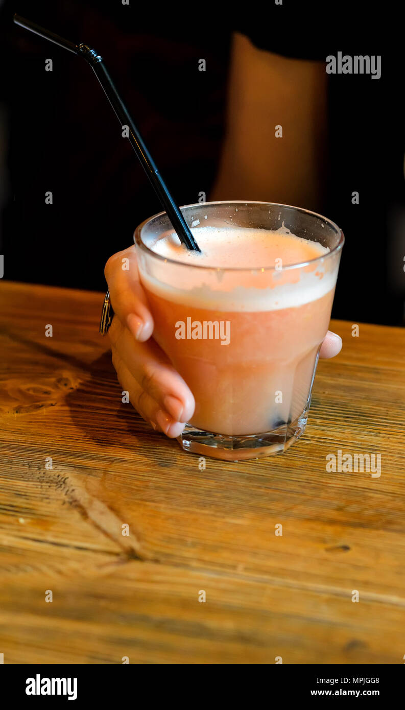 girl holding a glass of fresh grapefruit juice on a wooden table Stock Photo