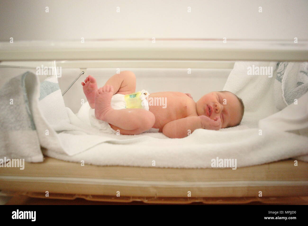 New born baby sleeps in hospital Perspex crib, age 0 months, August