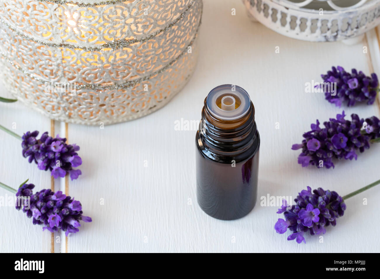A dark bottle of essential oil with fresh blooming lavender on a white ...