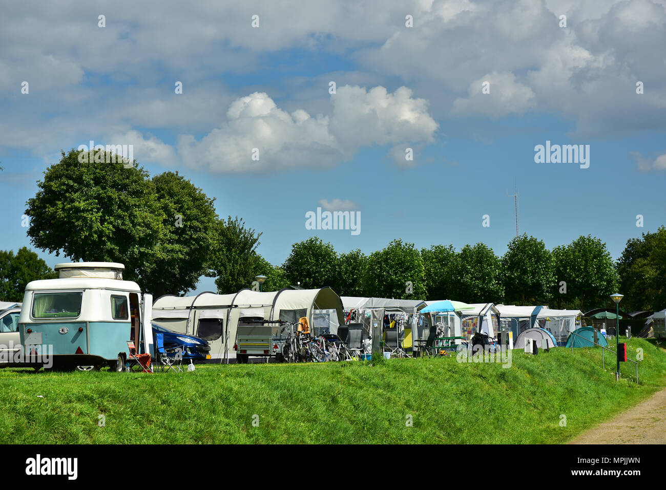 Vintage travel trailer in a row of tents on a campsite in Limburg, The Netherlands. Stock Photo