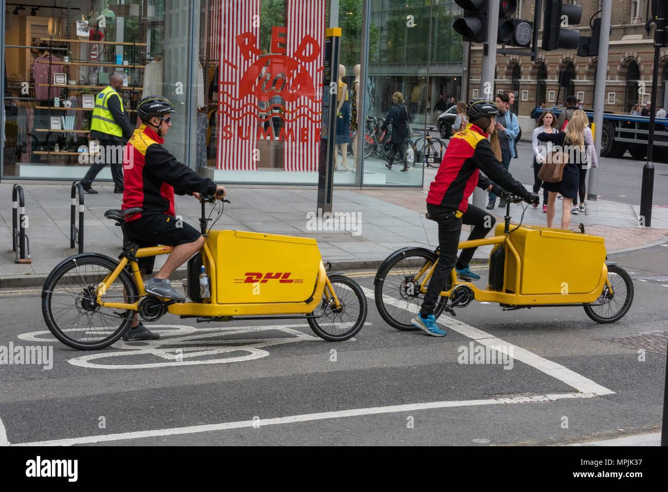 two DHL global logistics delivery drivers riding cycles to deliver parcels and courier services