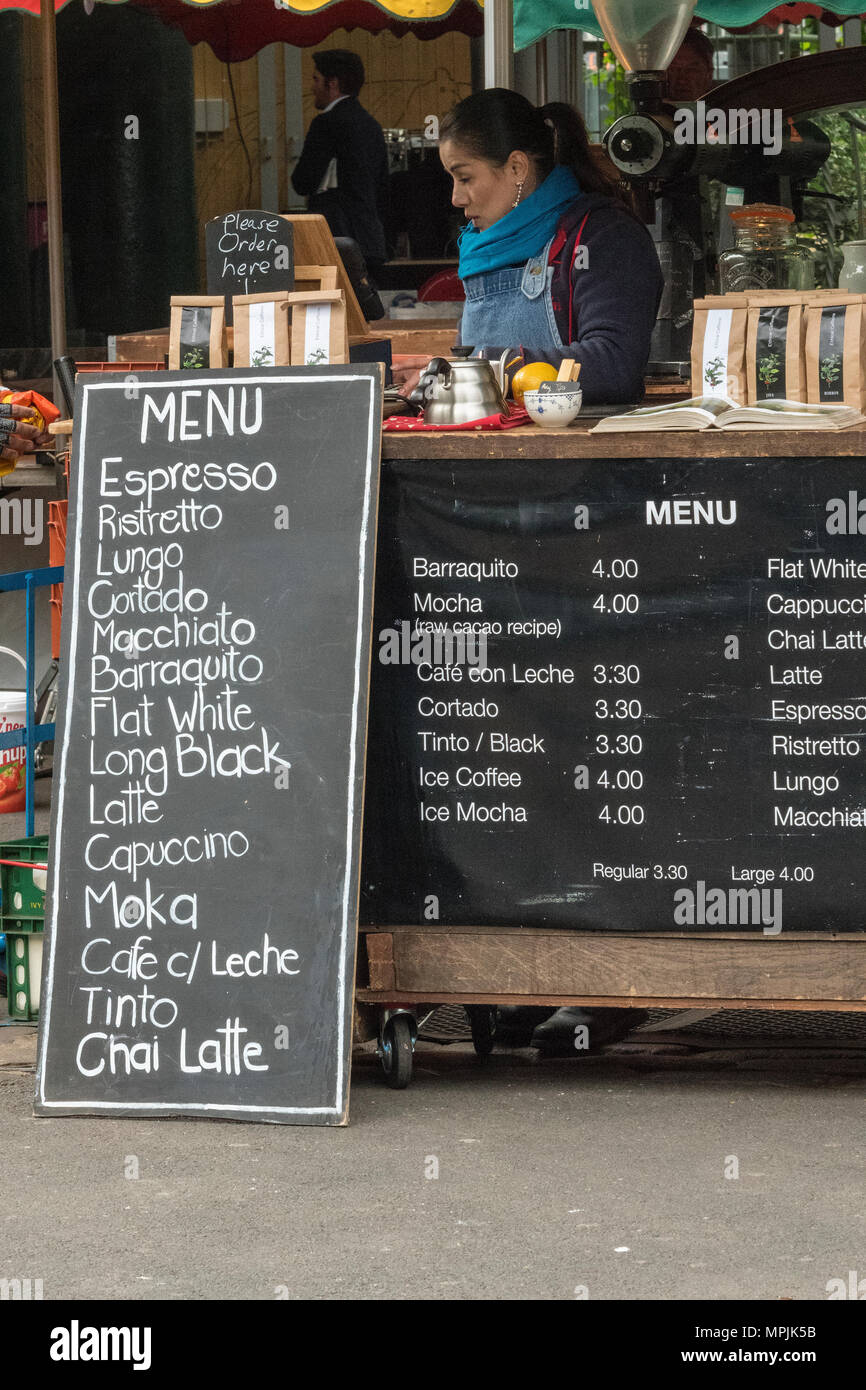a woman or lady selling coffee at a stall on borough market. different