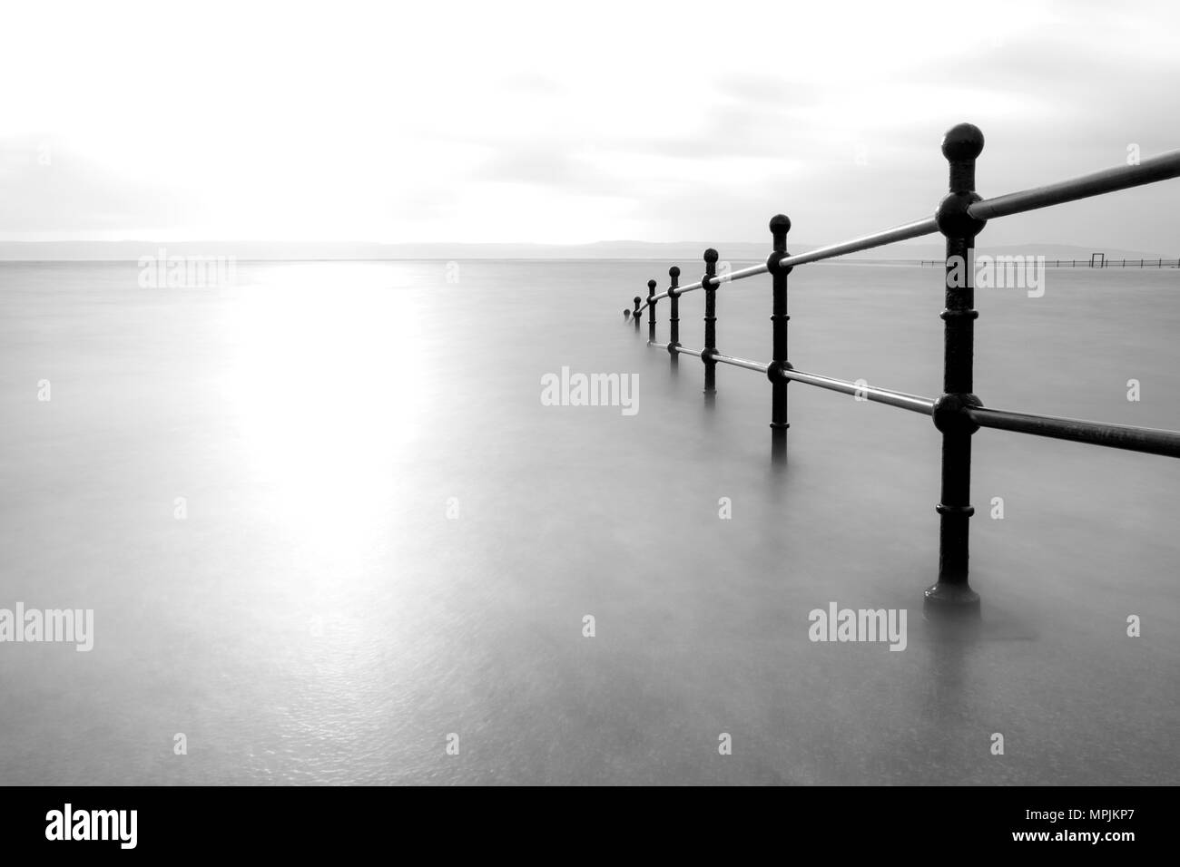Railings disappearing into the sea. Long exposure black and white. Stock Photo