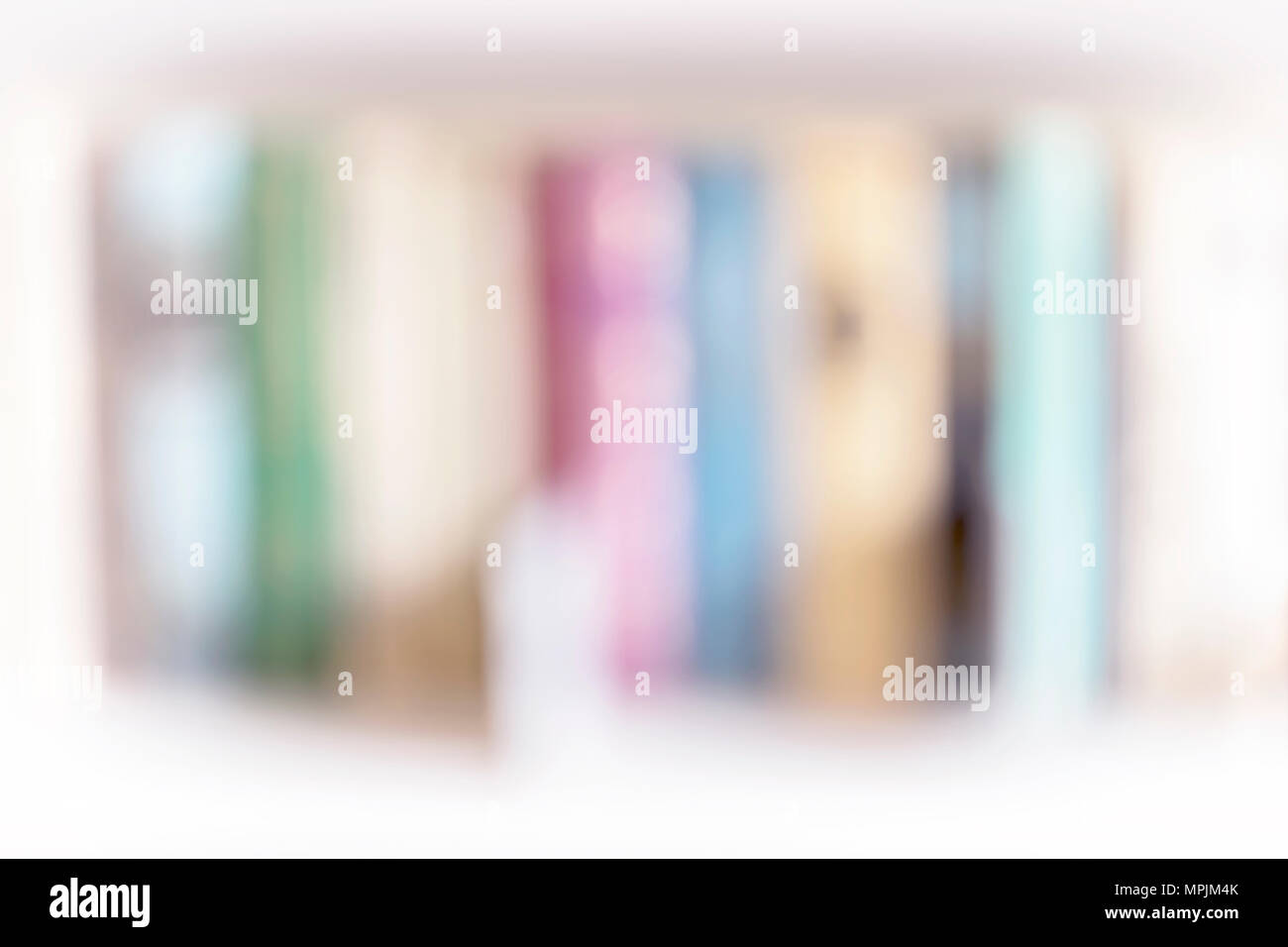 Row of colorful blank books, light blurred background. Blurred bookshelves of bookcase with books, studing, education. Light filter effect, soft focus Stock Photo