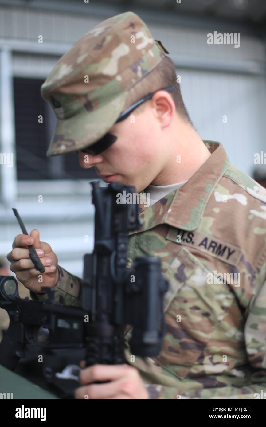 U.S. Army Pfc. Wenger, Combat Cameraman of the 982nd Combat Camera Company (Airborne), cleans his weapon on Fort Jackson, S.C., March 18, 2017. The 982nd Combat Camera Company (Airborne) is one of only two combat camera companies tasked with providing the Office of the Secretary of Defense, Chairman of the Joint Chiefs of Staff, and the military departments with a directed imagery capability in support of operational and planning requirements through the full range of military operations. (U.S. Army photo by Pfc. Keely Key) Stock Photo