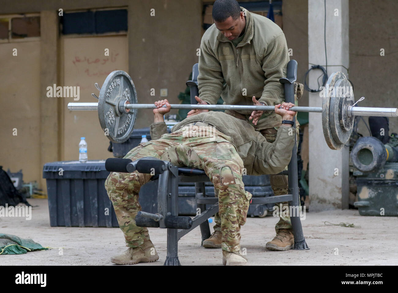 U.S. Army Sgt. Cameron Ragsdale, deployed in support of Combined Joint Task Force - Operation Inherent Resolve and assigned to 2nd Brigade Combat Team, 82nd Airborne Division, spots a partner while weightlifting during a break in operations at a tactical assembly area near Al Tarab, Iraq, March 17, 2017. The 2nd BCT, 82nd Abn, Div., enables their Iraqi security forces partners through the advise and assist mission, contributing planning, intelligence collection and analysis, force protection, and precision fires to achieve the military annihilation of ISIS. CJTF-OIR is the global Coalition to  Stock Photo