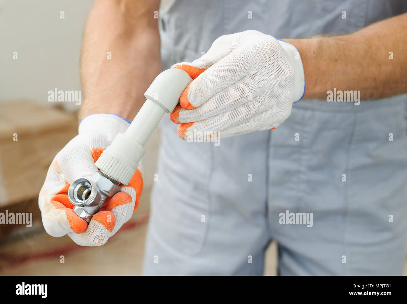 Soldering plastic pipe. A worker holds the valve and soldered pipe and