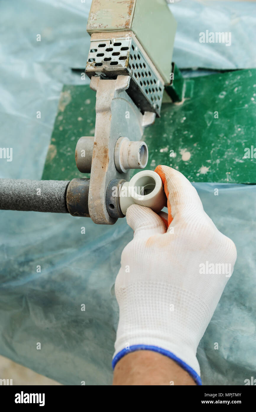 Soldering plastic pipe. A worker heats the pipe and knee for future connections using