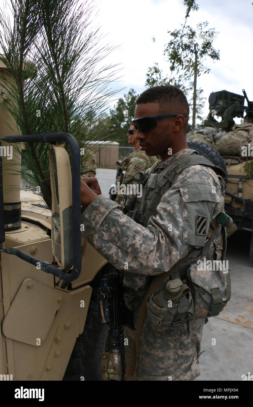 Spc. Maliik Johnson, cavalry scout with Bravo Troop, 6th Squadron, 8th Cavalry Regiment, 2nd Infantry Brigade Combat Team, 3rd Infantry Division, camouflages a humvee with foliage during a mounted gunnery range March 8, 2017 at Fort Stewart, Ga. 6-8 Cav. Soldiers qualified with mounted weapons in preparation for a squadron field training exercise next month. (U.S. Army photo by Sgt. Robert Harris/Released) Stock Photo