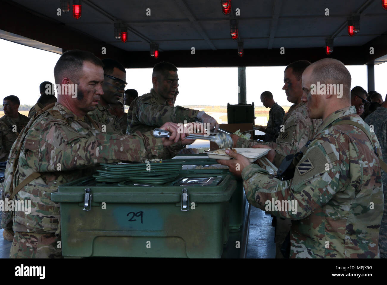 Leaders (left) of 6th Squadron, 8th Cavalry Regiment, 2nd Infantry Brigade Combat Team, 3rd Infantry Division serve dinner to their Soldiers during a mounted gunnery range March 8, 2017 at Fort Stewart, Ga. 6-8 Cav. Soldiers qualified with mounted weapons in preparation for a squadron field training exercise next month. (U.S. Army photo by Sgt. Robert Harris/Released) Stock Photo