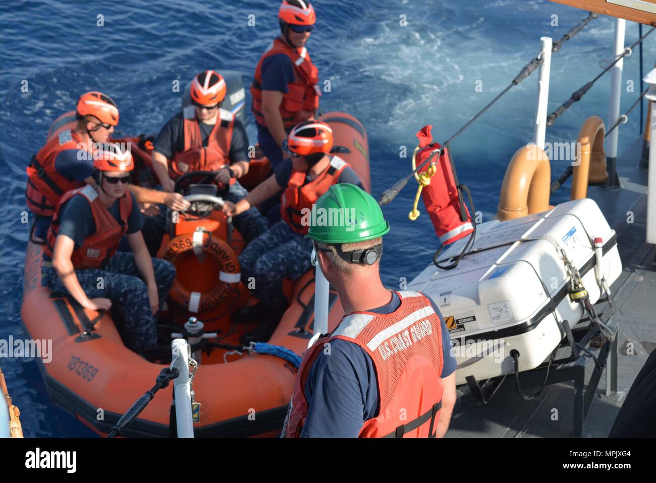 A Coast Guard crewmember aboard the Coast Guard Cutter Galveston Island (WPB 1349) prepares to assist U.S. Naval Sea Cadet Corps cadets disembark a small boat after conducting training off of Honolulu, March 11, 2017. The USNSCC is a Navy-based organization, which serves to teach teens about sea-going military services, U.S. naval operations and training, community service, discipline and teamwork. (U.S. Coast Guard photo by Petty Officer 1st Class Joe Jorgenson/Released) Stock Photo