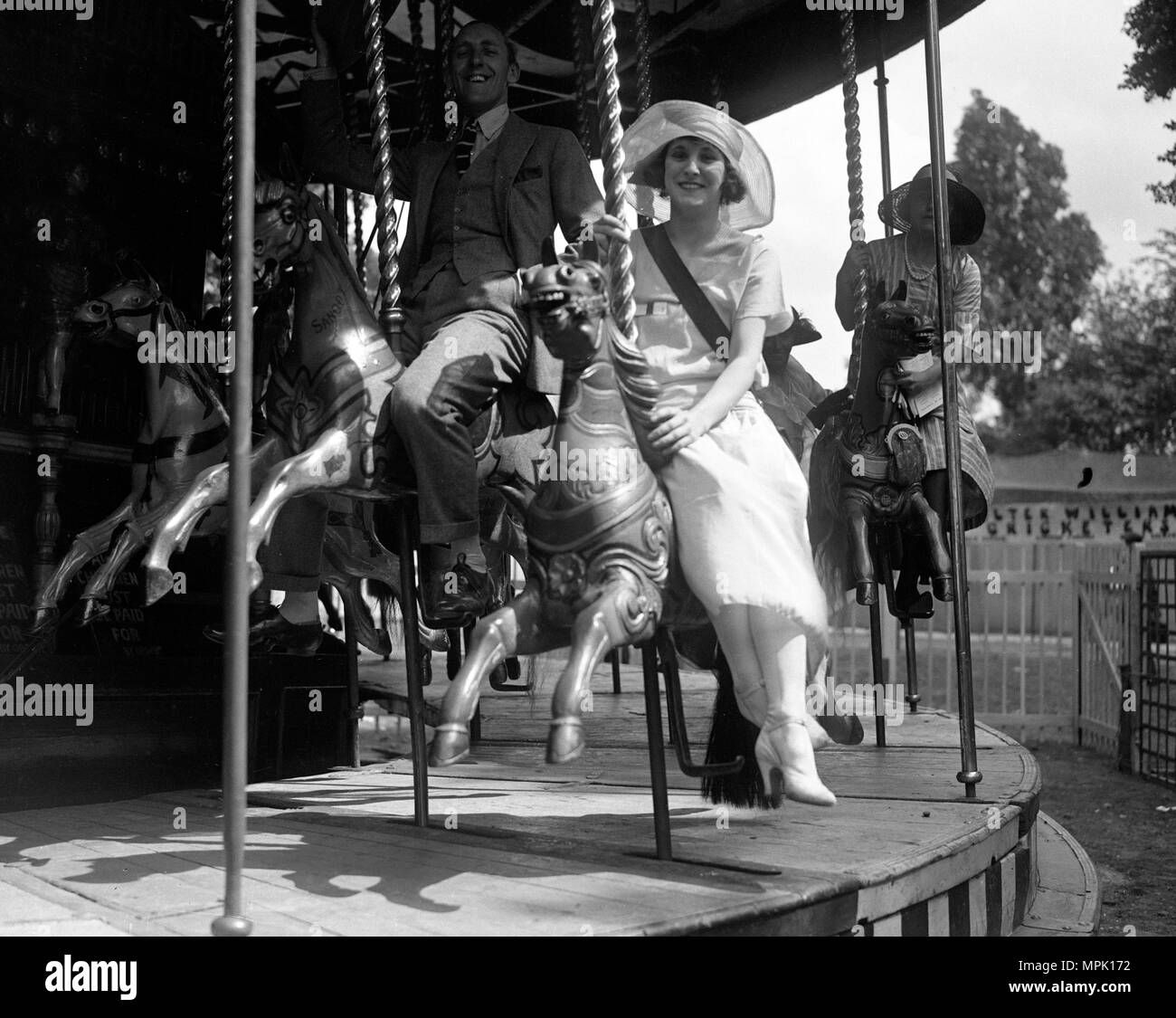 Mary Leigh and Jack Hulbert on a carousel at a theatrical garden party in Chelsea. Stock Photo