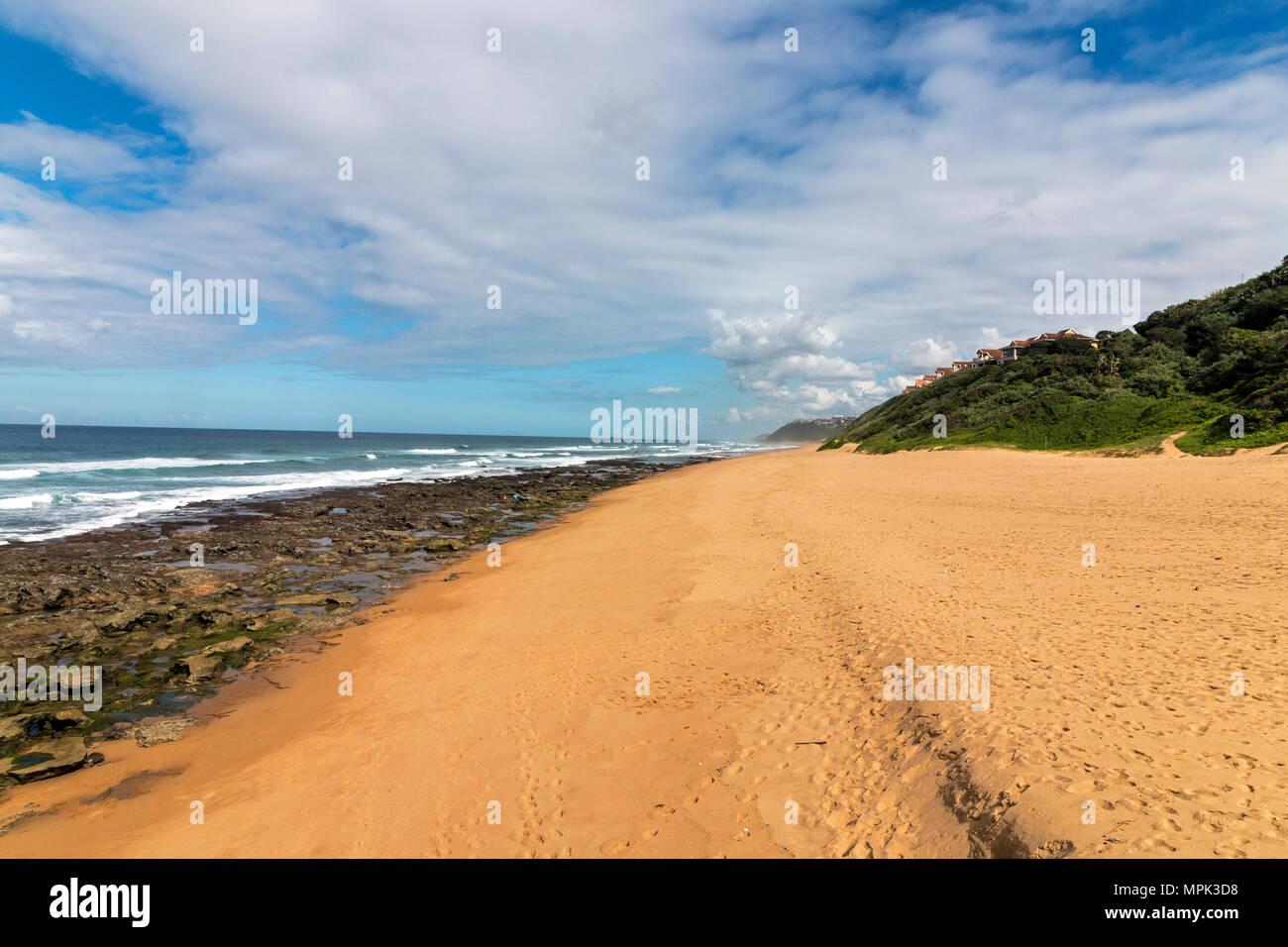 Low tide rocky beach waves and ocean against blue cloudy sky seascape