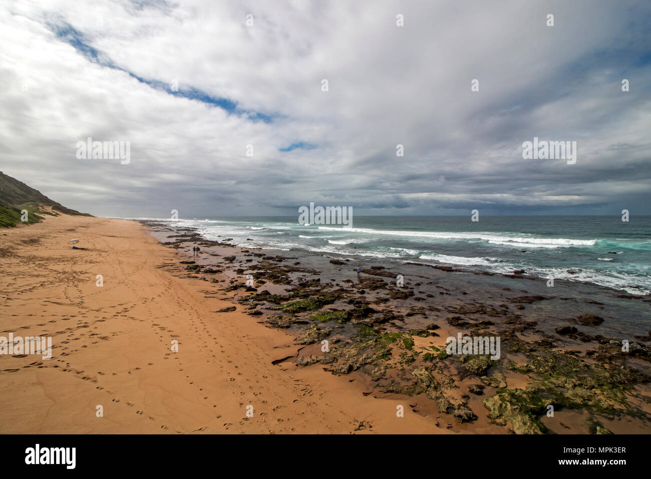 Low tide rocky beach waves and ocean against blue cloudy sky seascape