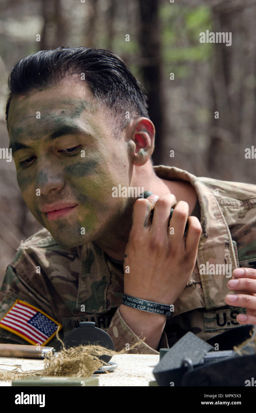 A Soldier applies camouflage face paint and adjusts equipment during Expert  Infantryman Badge (EIB) training at Fort Jackson. The exercise teaches  infantrymen to apply camouflage principles to personal gear, uniforms, and  exposed