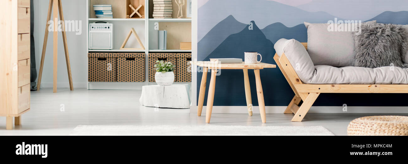 Panorama of a wooden frame sofa and a side table by a mountains wallpaper  in a scandinavian style, white living room interior Stock Photo - Alamy