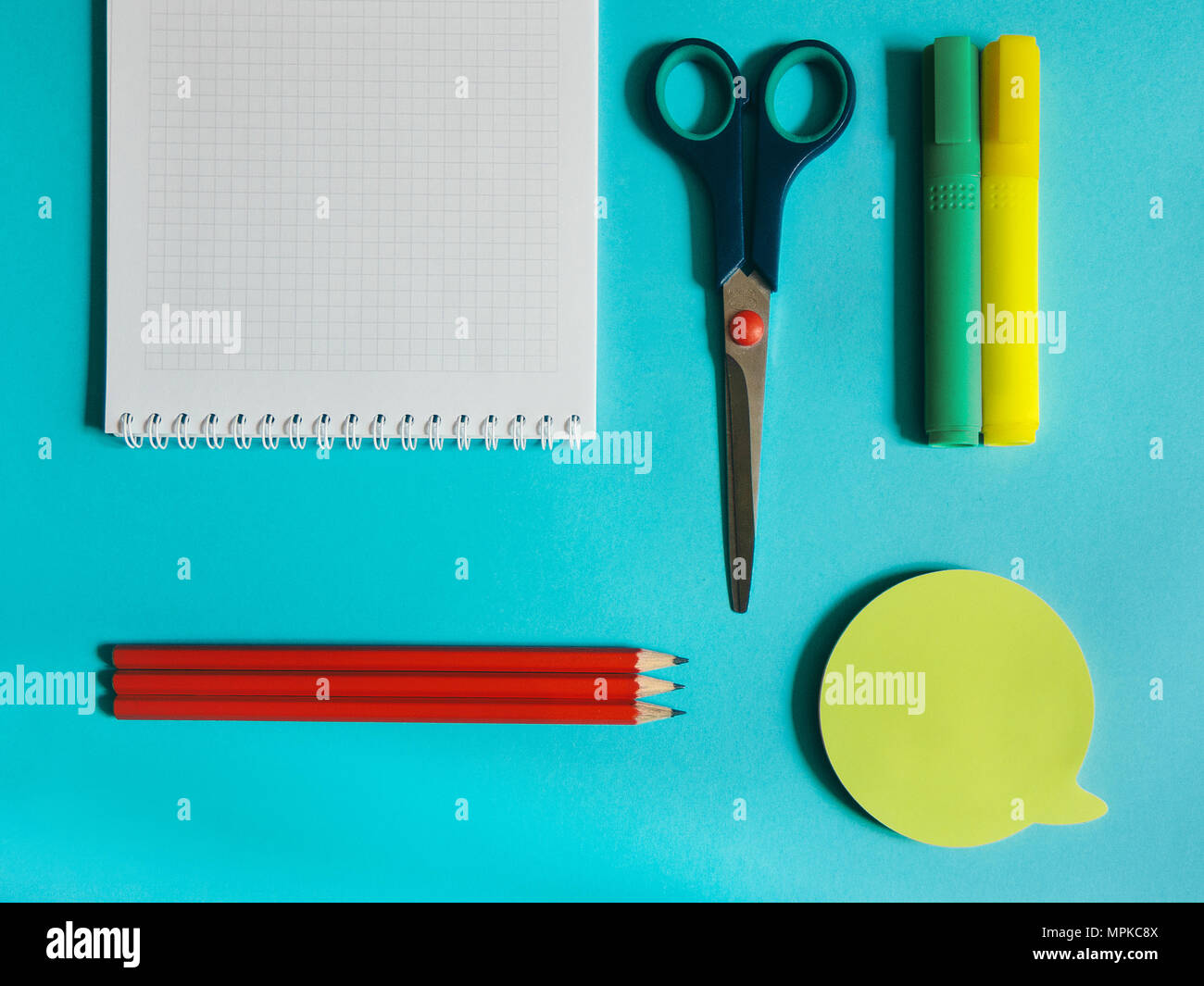 School supplies photo Notebook, stationery scissors, markers, pencils and stickers are lying on the blue desk Stock Photo